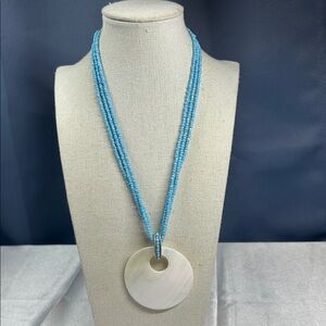 Avon necklace featuring a shell pendant on a three-strand blue seed bead chain